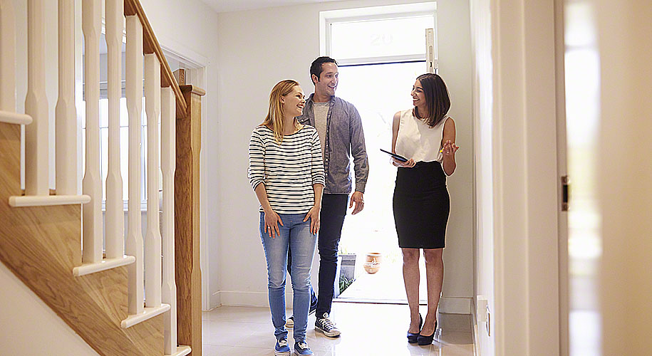 Realtor Showing Young Couple Around Property For Sale – Via Modem